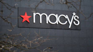 Macy's 商店標誌，灰色牆上紅色星星，由光禿樹枝框住 — iMac 壁紙