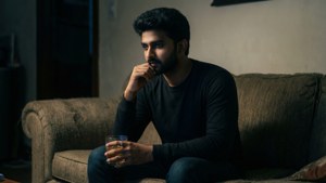 男人坐在沙發上在昏暗房間裡拿著飲料