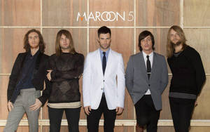 Maroon 5 的五位成員在木牆前擺姿勢，並展示樂隊名稱。 — 桌面 壁紙