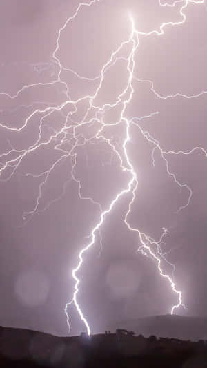 強大的閃電照亮了黑暗山丘上方暴風雨般的紫色天空。 — 閃電麥坤 壁紙
