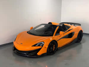橙色McLaren 570S Spider敞篷跑車，帶黑色飾邊，停在室內。 — 4:3 壁紙