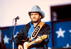 Merle Haggard 在星空背景的舞台上彈吉他。 — 音樂 壁紙