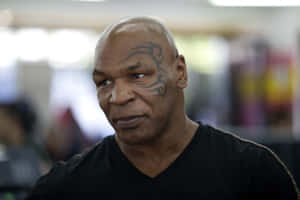 Mike Tyson 頭上有部落圖騰紋身，室內穿著黑色襯衫。 — MacBook Pro M3 壁紙