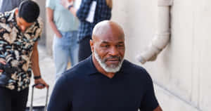 Mike Tyson 走在城市小巷中，身後跟著一位攝影師。 — 麥克·泰森 壁紙