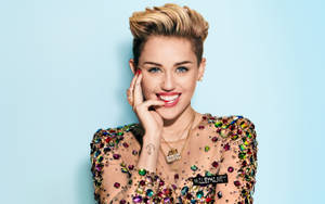 Miley Cyrus 穿著寶石上衣微笑，手靠近臉部。 — 麥莉·希拉 壁紙
