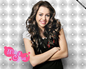 Miley Cyrus 在CD背景前微笑，雙臂交叉。 — 麥莉·希拉 壁紙