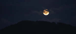 滿月在多雲的夜空下，從黑暗的山脈後升起。 — 簡約暗黑美學 壁紙