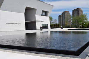 現代博物館建築，設有水景，附近有人走動。 — MacBook Pro 14 壁紙