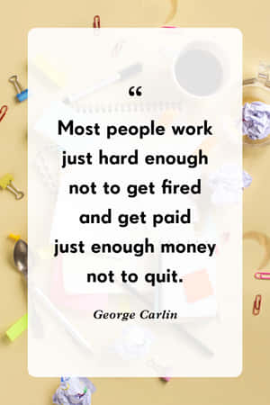 辦公桌上有咖啡杯、筆和皺巴巴的紙，並展示 George Carlin 關於工作和金錢的名言。 — iPhone Duo 壁紙