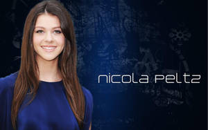 Nicola Peltz 身穿藍色連衣裙微笑，名字顯示在深色頹廢背景上。 — 女演員 壁紙