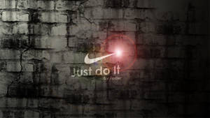 Nike 標誌帶有 'Just do it' 口號在裂縫磚牆上發光。 — 就去做吧 壁紙