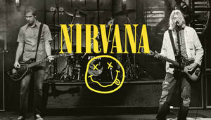 Nirvana 樂團在舞台上現場表演，帶有黃色笑臉標誌疊加。 — 涅槃 壁紙