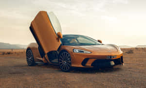 橙色McLaren跑車，蝴蝶門打開，停在沙漠中，日落時分。 — 福特 壁紙