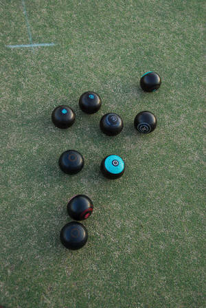 Black and teal lawn bowls on green artificial turf for outdoor game. — 運動 壁紙
