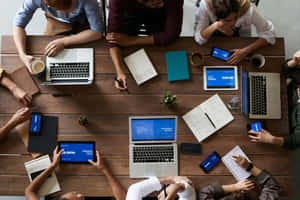 Team of professionals working together at a wooden table with laptops and notebooks. — 筆電 壁紙