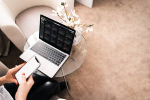 Person using laptop and phone on glass table in modern living room. — 筆電 壁紙