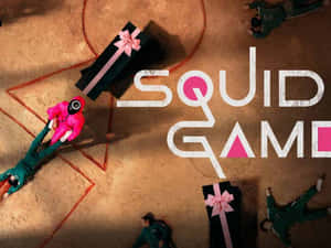 Players in green and pink uniforms lie on dusty ground around giant gift boxes. — 067 魷魚遊戲 壁紙