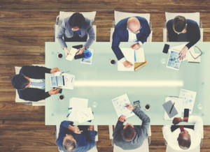 Six business professionals in suits collaborating around a glass conference table. — 辦公室 壁紙