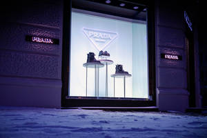 Prada 商店櫥窗在雪夜城市中展示鞋子。 — Prada 壁紙