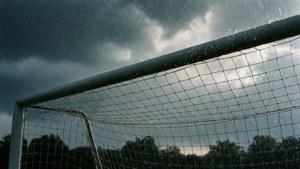 暴風雨天空下，足球球門網在暴雨中，背景有樹木
