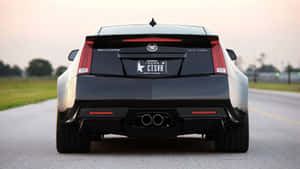 黑色Cadillac CTS-VR在黃昏時分道路上的後視圖，天空粉紅。 — 凱迪拉克 壁紙