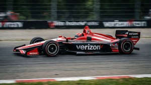 紅黑相間的Verizon IndyCar在背景模糊的賽道上比賽。