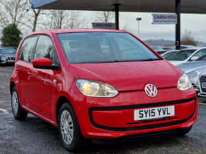 紅色Volkswagen up!停放在潮濕的汽車經銷商場地中。 — 福斯汽車 壁紙
