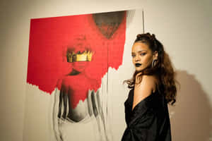 Rihanna 身穿黑色緞面連衣裙，化著大膽的妝容，站在一幅帶有戴皇冠人物的紅白藝術作品旁邊。 — 黑色愛情 壁紙