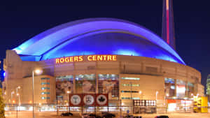 Rogers Centre 體育場在夜晚亮燈，背景有 CN Tower。 — 多倫多藍鳥隊 壁紙