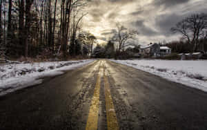 一條濕漉漉的冬日道路，帶有黃色標線，在黃昏時分通往一間被雪和光禿樹木環繞的房屋。 — 冬季風景 壁紙