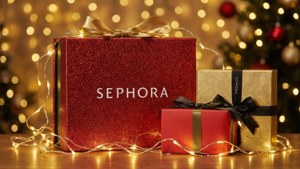 Sephora禮物盒用紅色、金色和黑色絲帶包裹，帶有仙女燈，放在木桌上。