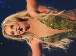 Shakira 在舞台上唱歌，身穿閃亮綠色服裝，金色長髮。 — 小甜甜布蘭妮 壁紙