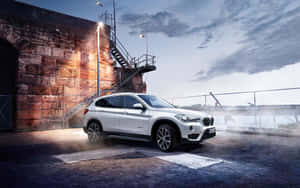白色BMW SUV在黃昏時停泊在石頭倉庫旁，帶有迷霧和戲劇性的燈光。 — Steam Deck OLED 壁紙