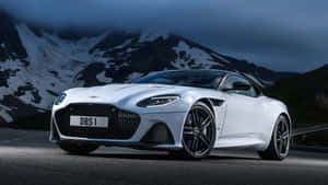 暮色中，白色Aston Martin DBS跑車停在山路上，背景有白雪覆蓋的山峰。 — 奧斯頓馬丁 壁紙