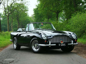 經典黑色Aston Martin DB5敞篷車停泊在森林道路上。 — 奧斯頓馬丁 壁紙