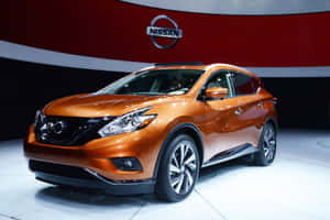 橙色日產Murano SUV在紅色和白色背景的車展中展示。 — 日產 壁紙