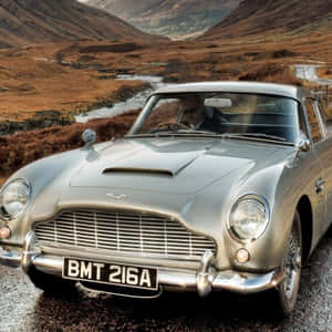 銀色經典Aston Martin DB5停放在河邊濕滑的山路上。 — 奧斯頓馬丁 壁紙