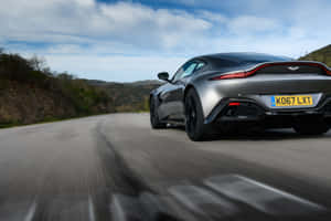 銀色Aston Martin Vantage在山路上疾馳，帶有動態模糊效果。 — Surface Pro 壁紙