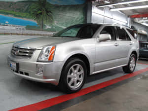 銀色 Cadillac SRX SUV 停放在車庫，牆上有熱帶壁畫。 — 凱迪拉克 壁紙