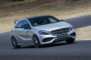 銀色 Mercedes-Benz A45 AMG 在日落時分的蜿蜒道路上疾馳。 — Surface Laptop 壁紙