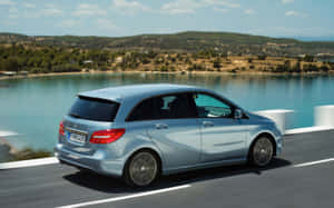 銀色 Mercedes-Benz B-Class 在近水的海岸道路上行駛。 — Steam Deck 壁紙