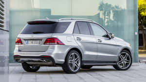 銀色 Mercedes-Benz GLE SUV 停放在玻璃建築旁，窗戶有棕櫚樹倒影。 — Pro Display XDR 壁紙