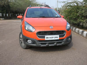 橙色 Fiat Panda 停在街上，有綠化和條紋路緣。 — 飛雅特 壁紙