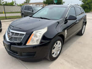 黑色 Cadillac SRX SUV 停放在混凝土停車場。 — 凱迪拉克 壁紙