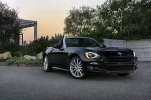 黑色Fiat 124 Spider敞篷車在戶外日落時停放。 — 飛雅特 壁紙