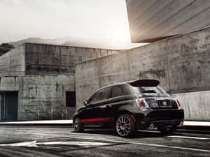 黑色Fiat 500帶有紅色條紋，停放在混凝土建築附近。 — 飛雅特 壁紙