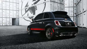 黑色Fiat 500帶紅色條紋，停放在白色貨櫃之間。 — 飛雅特 壁紙