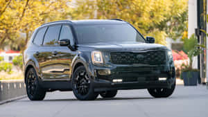黑色Kia Telluride SUV停放在戶外，後面有秋樹。 — 起亞 壁紙