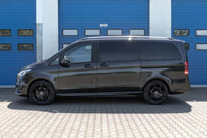 黑色 Mercedes-Benz V-Class 客貨車停放在藍色車庫門前。 — Surface Pro 壁紙