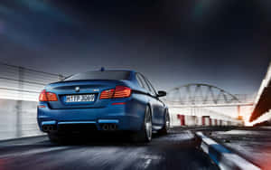 藍色BMW M5在黃昏時分於賽道上飛馳，帶有動態模糊。 — MacBook Pro 13 壁紙